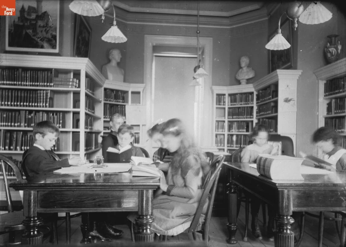 Photo taken by Jenny Young Chandler of young people sitting at tables and reading in the Newark library