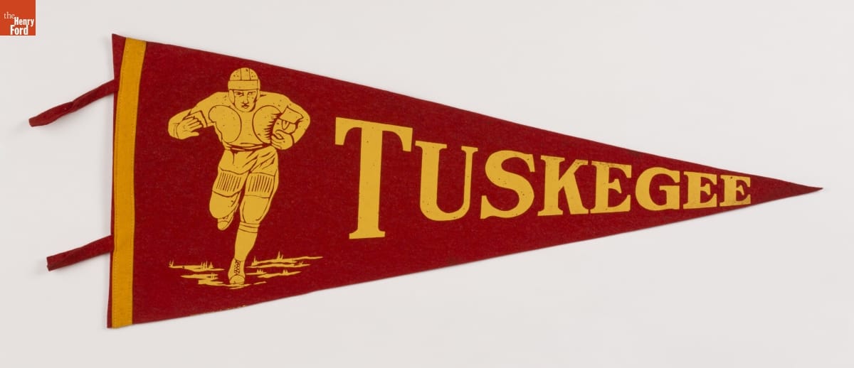 Red triangular pennant with yellow text "TUSKEGEE" and image of football player