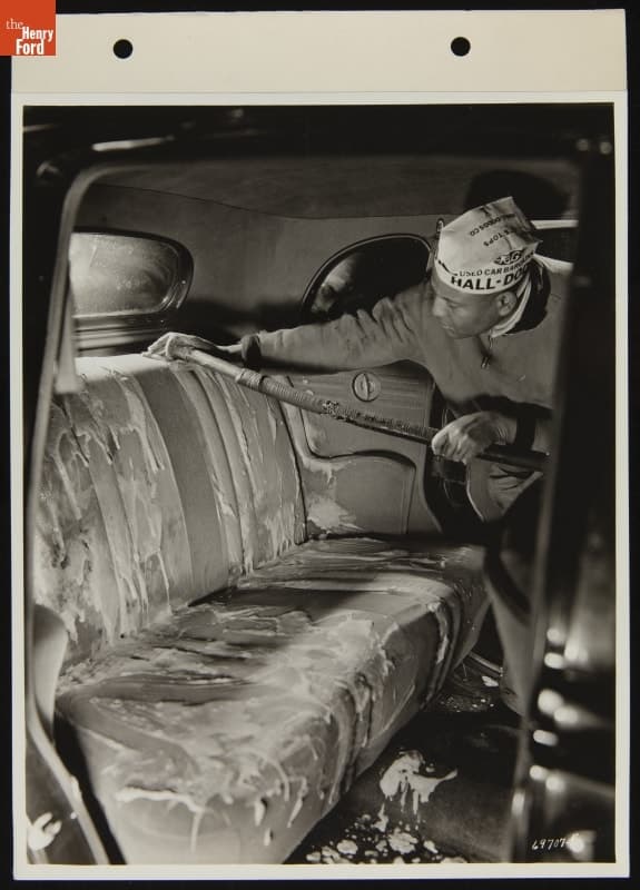Mechanic Cleaning Used Car Seat Upholstry at Hall-Dodds Dealership, January 1938