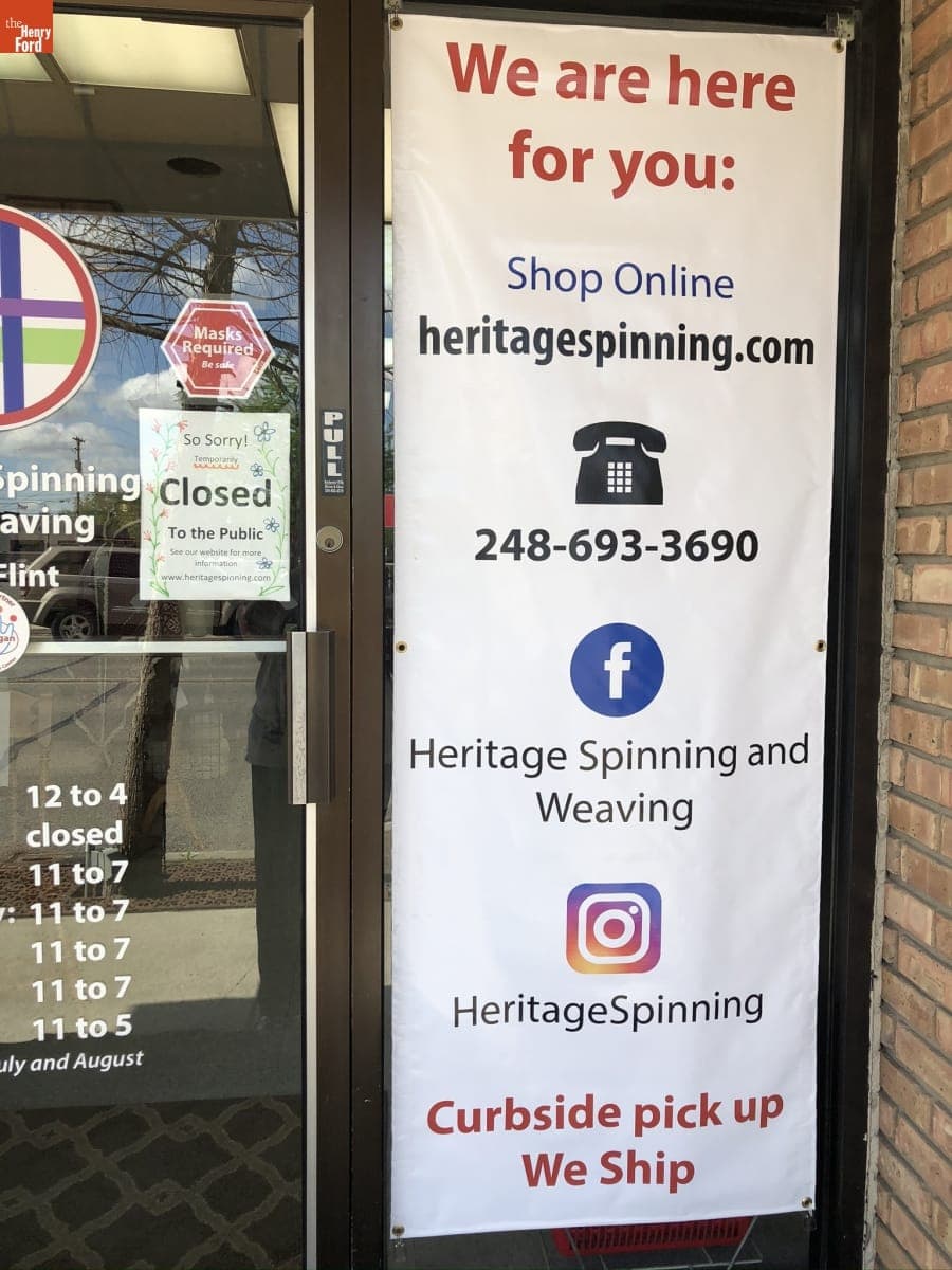 Banner in Window of Heritage Spinning & Weaving Shop, "We are here for you...Curbside pick up/We ship," 2020