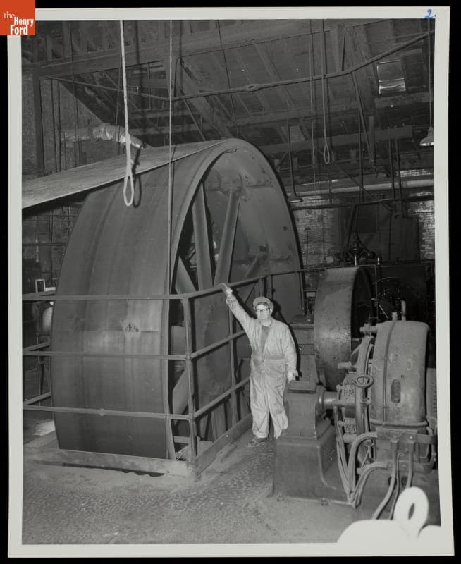Machine Operator Standing Next to Flywheel of a Stationary Steam Engine, circa 1950