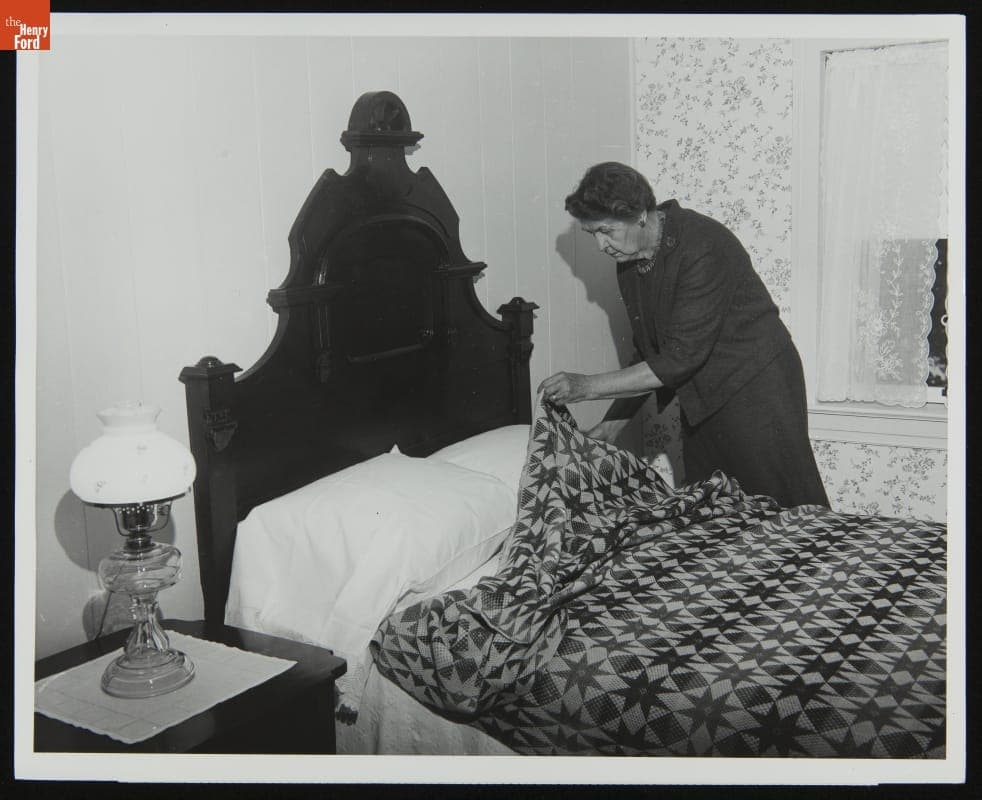 Catherine Ake, Granddaughter of Catherine Firestone Places a Quilt on a Bed in Firestone Farm at its Original Site, Columbiana County, Ohio, 1965