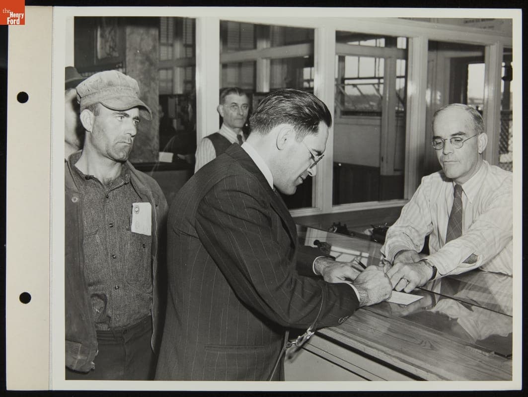 Ford Employee Sylvester Rypkowski Filling Out Paperwork, Holding Service Dog "Blackie's"Leash, October 1942