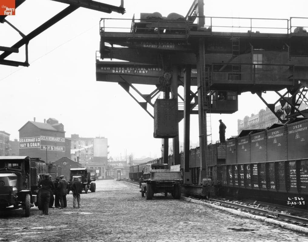 Crane Unloading Cargo from Railroad Cars into a Mack Model AC Dump Truck. 1927