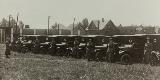 Row of Model T ambulances, each with a woman in uniform standing before it