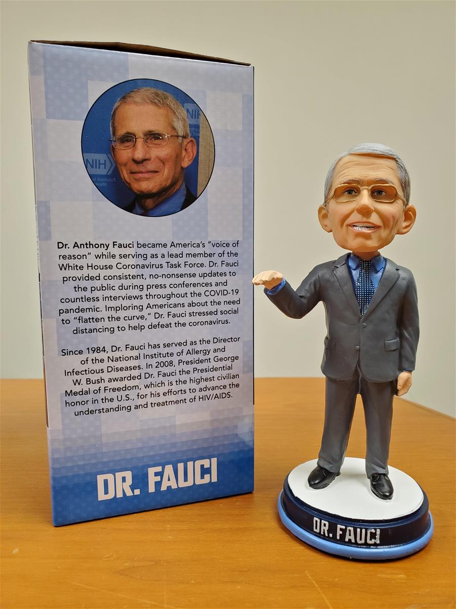 Dr. Anthony Fauci bobblehead and packaging Large-headed figurine of man in gray suit with glasses, next to box containing photo of man's head and text