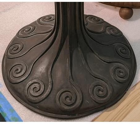 Before and after shots of the lamp base GIF rotating through two photos of round lamp base with swirled pattern; the first is dark and dull and the second is lighter and shiny