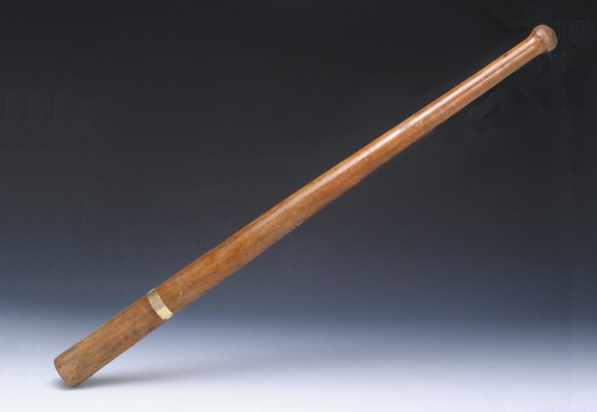 Long, thin, wooden baseball bat with a small gold plaque on one end