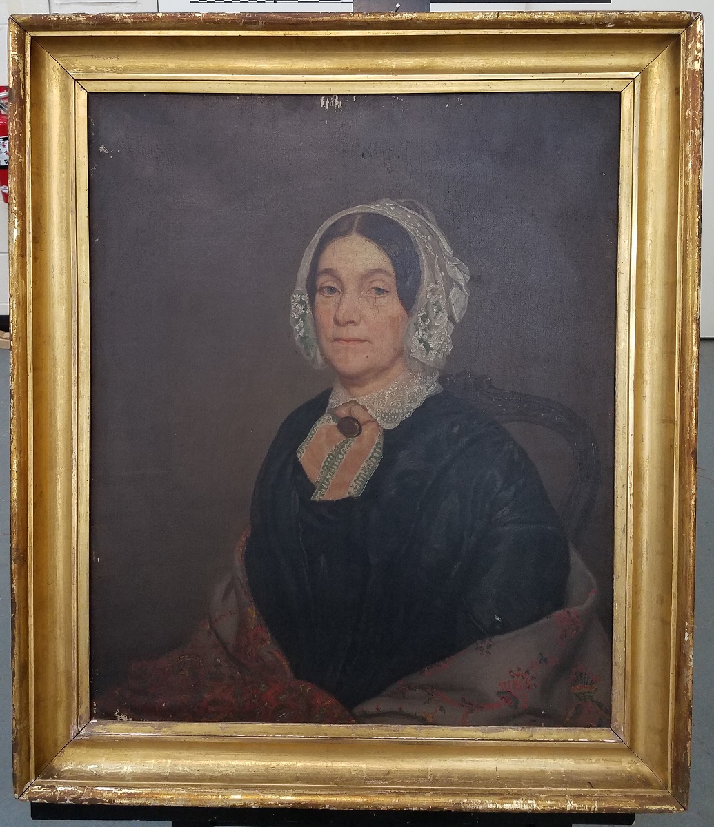 “Lady in a Lace Bonnet" before conservation treatment Painting of woman in black dress, shawl, and lace bonnet in gold frame