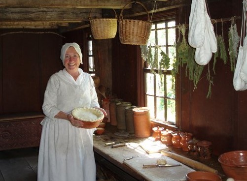 Woman holds a pie in a rudimentary kitchen
