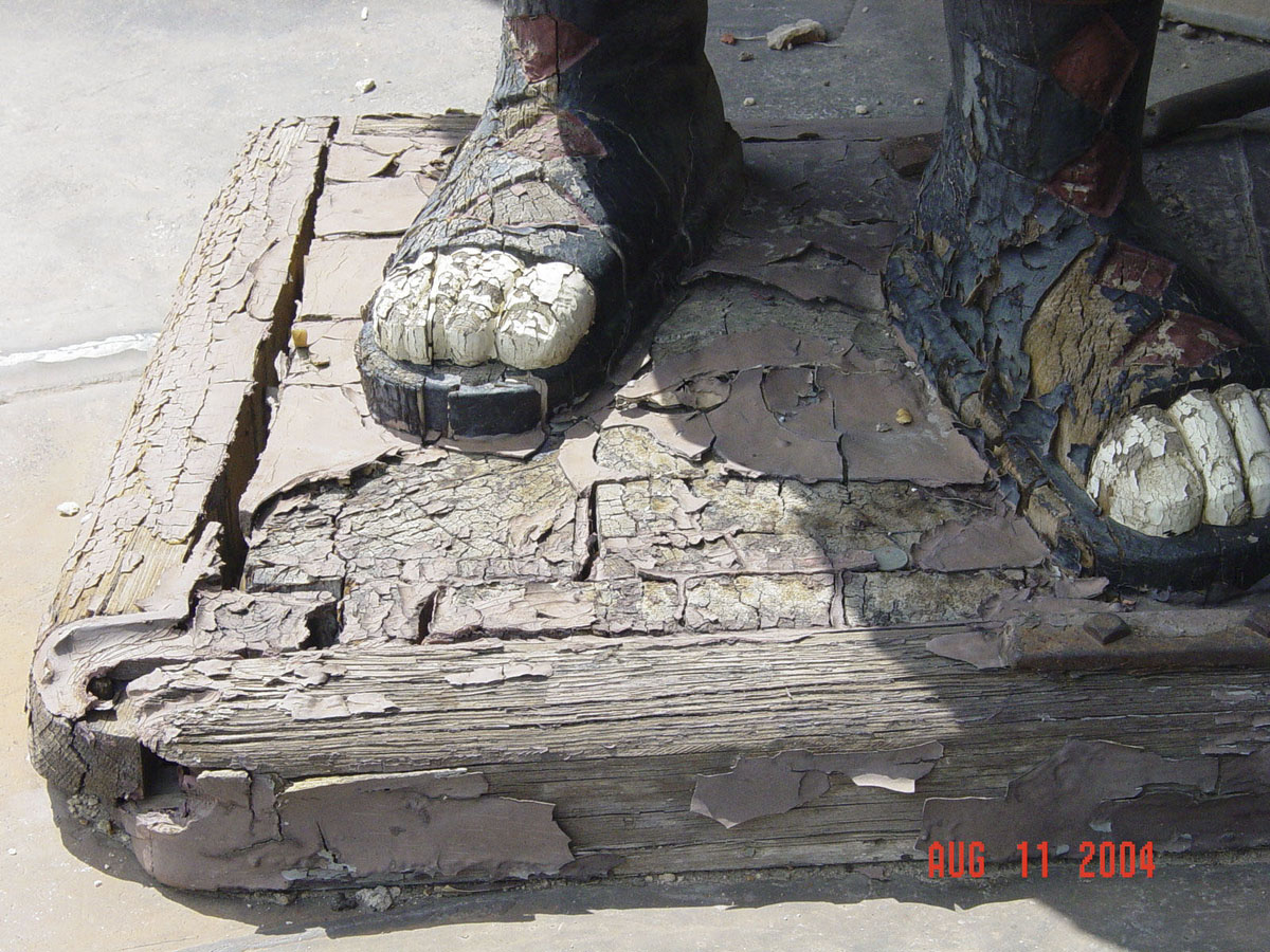 Statue base and sculpted feet of very cracked wood