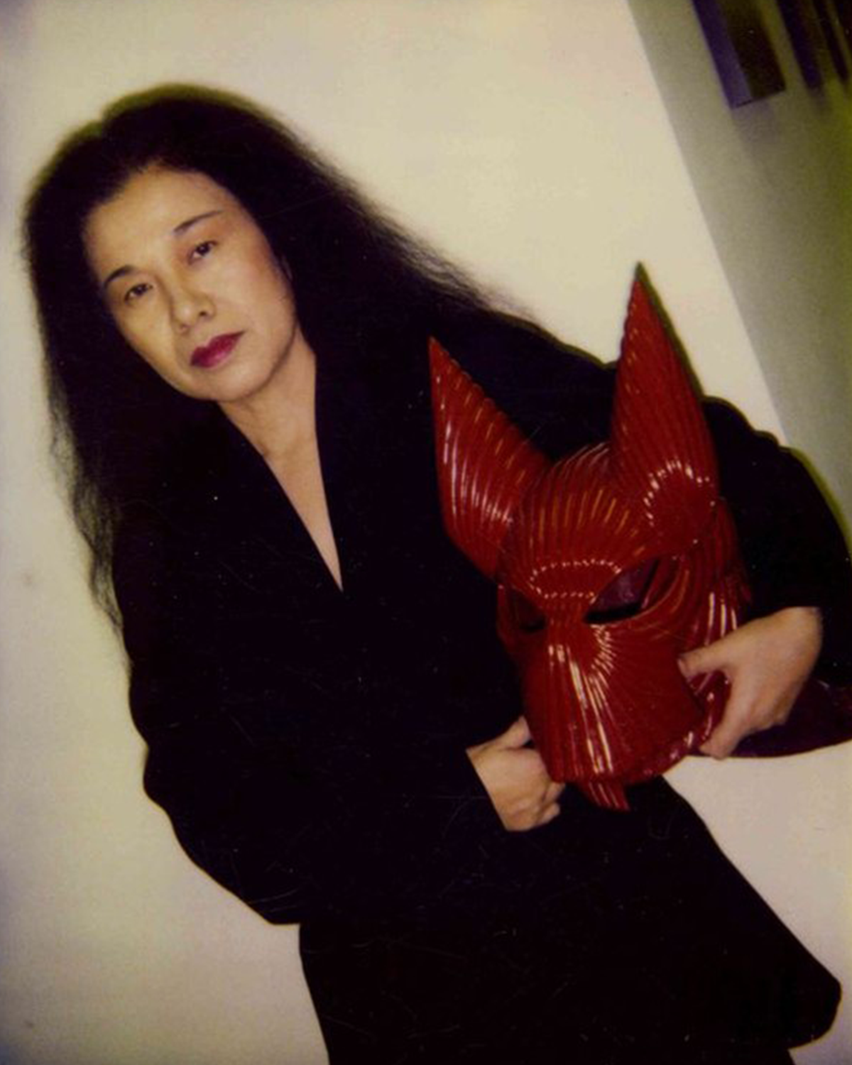 Eiko Ishioka, posing with the mask that pairs with Dracula’s armored suit