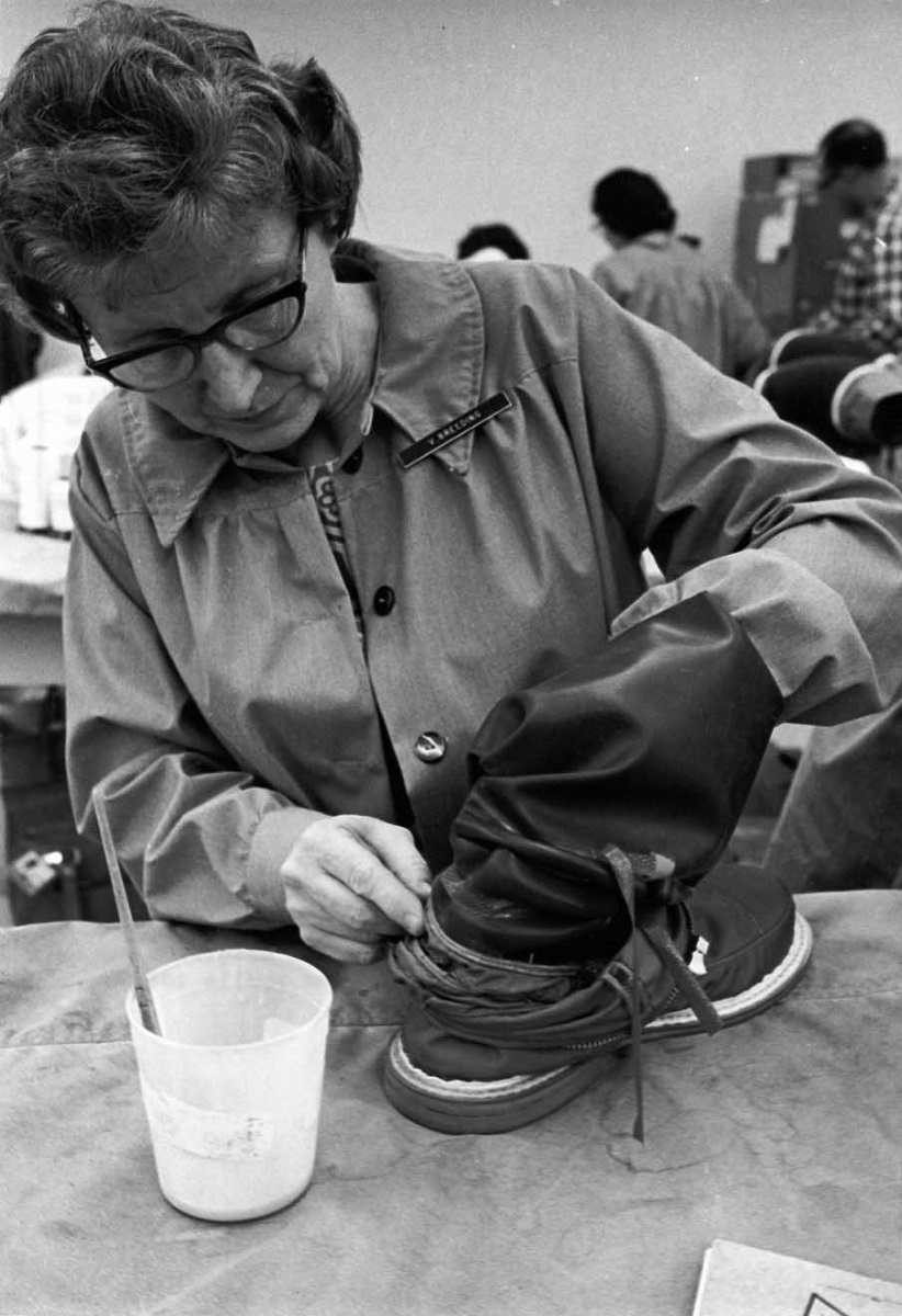 ILC Dover employee Velma Breeding working on space boots Woman in a smock with nametag works with her hand inside a boot; a cup with a brush in it sits nearby