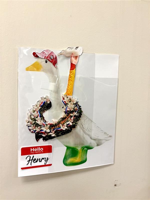 Paper goose wearing baseball cap and a wreath around its neck