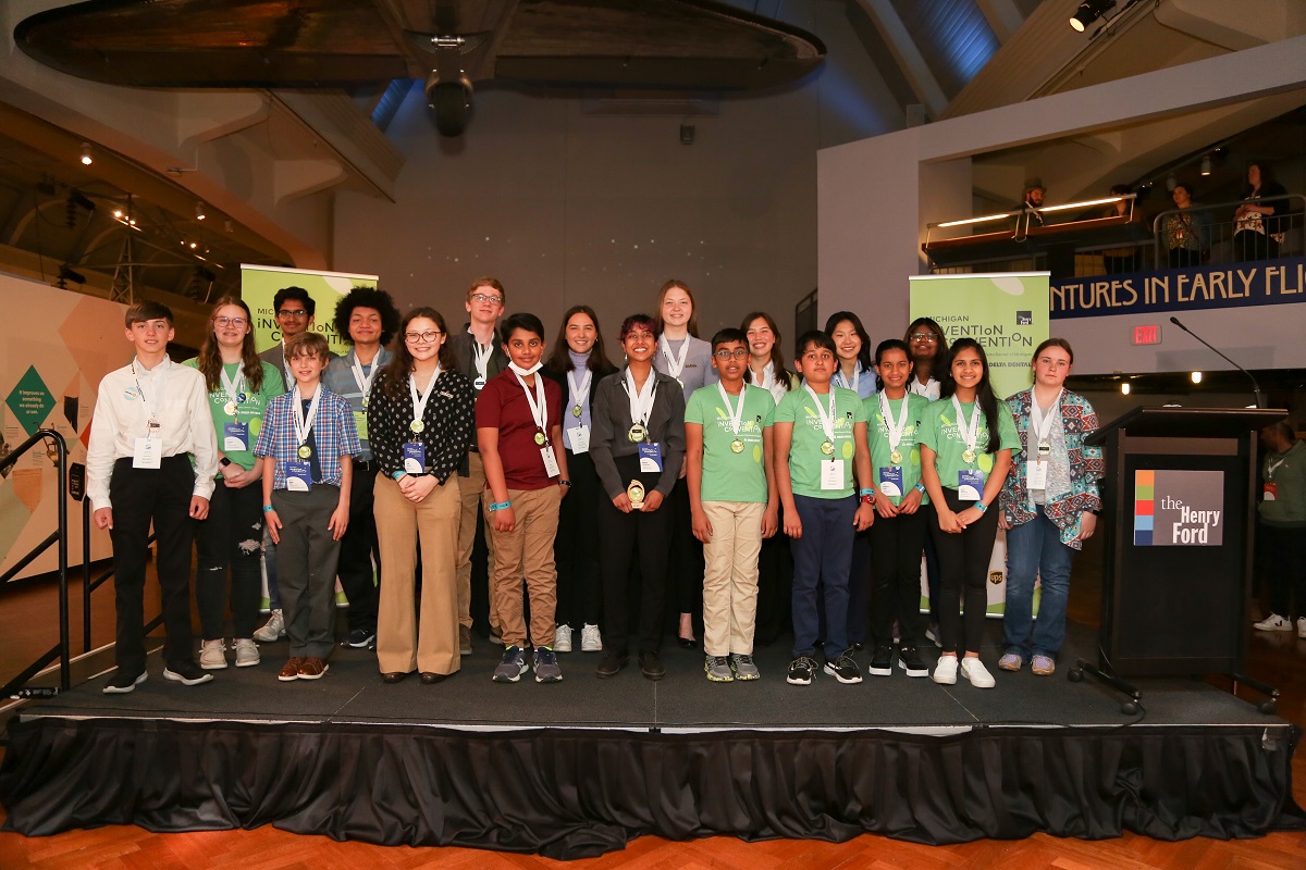 A group of children stand on a low stage and pose for the camera