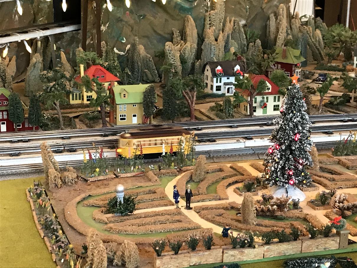 Model train layout in Henry Ford Museum of American Innovation, decorated for the holidays Model train layout with train tracks, train car, greenery, and houses, with Christmas decorations