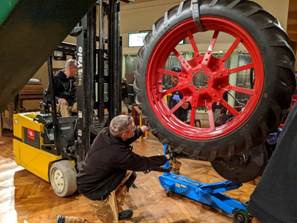 Removing the rubber wheels Large tire dangling from forklift, being guided by a man kneeling on the ground