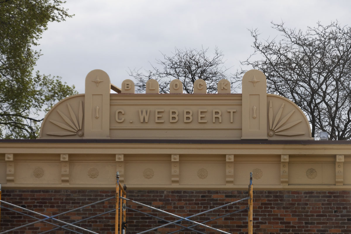 Building roof with large sign with decorative elements and text reading 