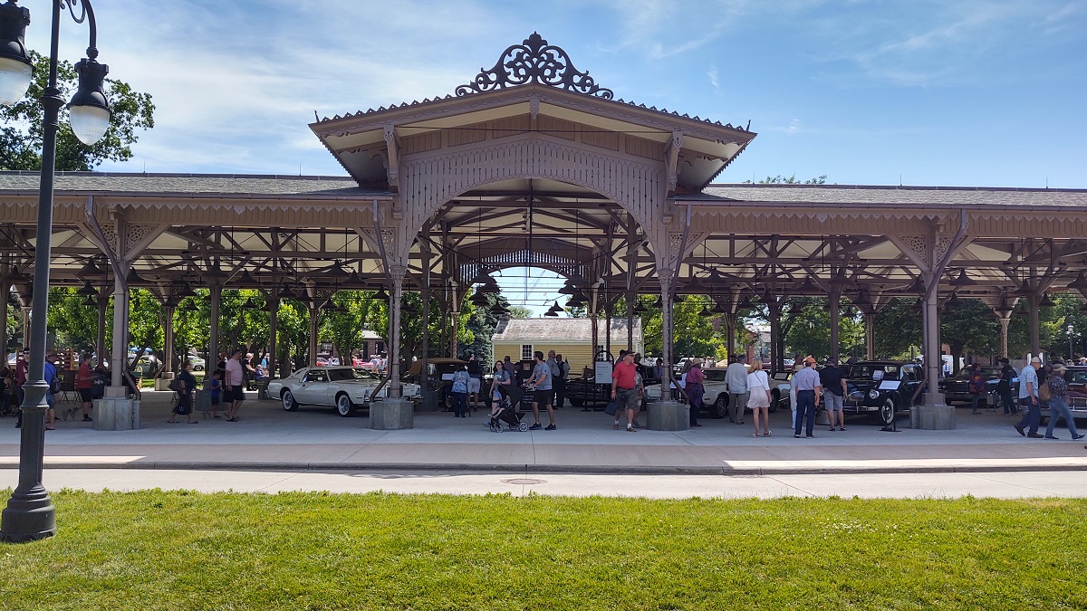 Large low building with open sides, filled with cars and spectators