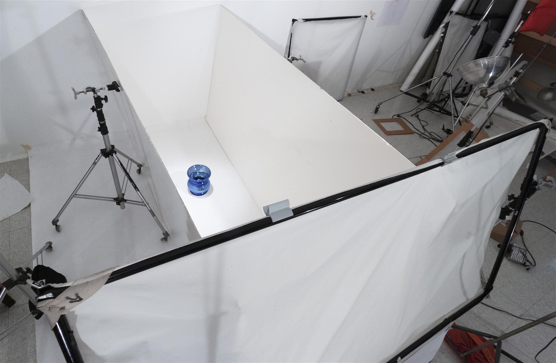 Aerial shot of space blocked off with white boards and paper; blue spittoon inside space; photography equipment outside