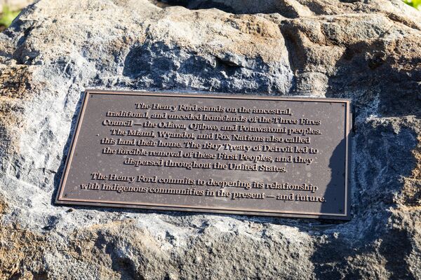 Land Acknowledgement Plaque Bronze land acknowledgement plaque mounted on a large natural boulder. The plaque states that The Henry Ford stands on the ancestral, traditional, and unceded homelands of the Three Fires Confederacy—the Odawa, Ojibwe, and Potawatomi peoples—and affirms a commitment to strengthening relationships with Indigenous communities in the present and future.