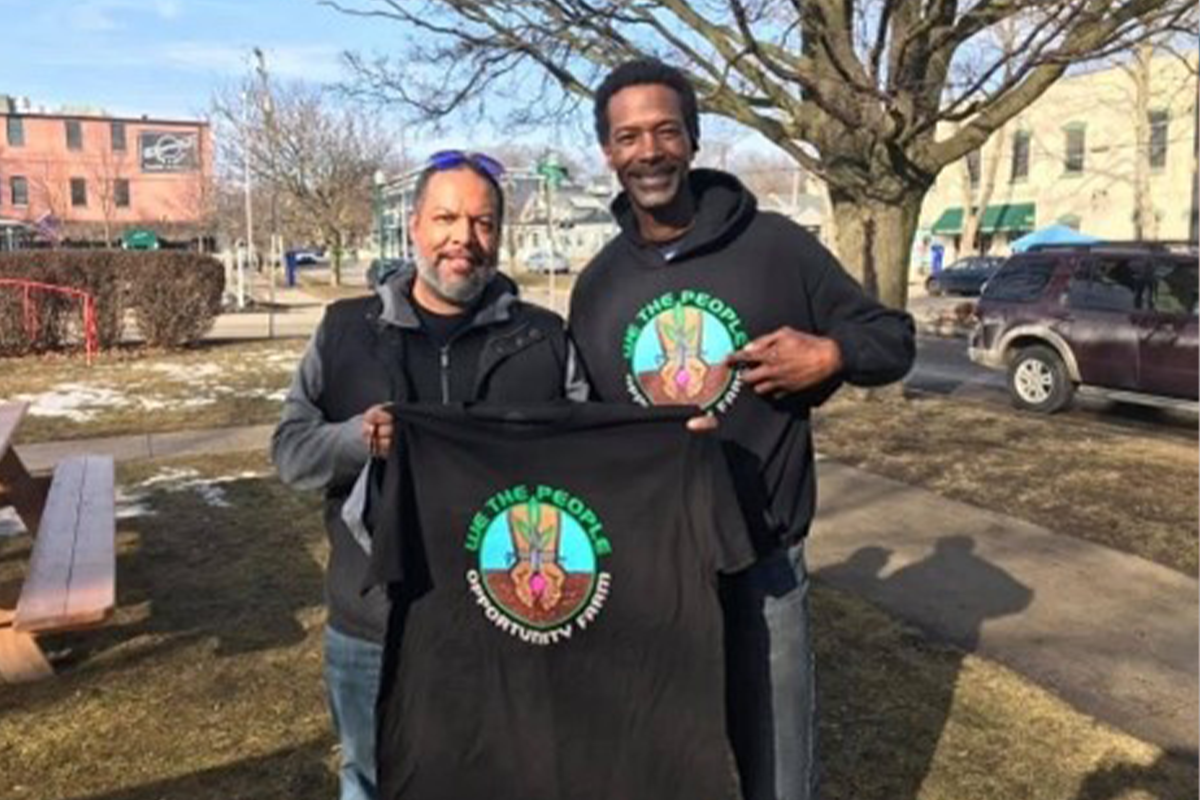 Brent Embry and Melvin Parson holding up a black tshirt
