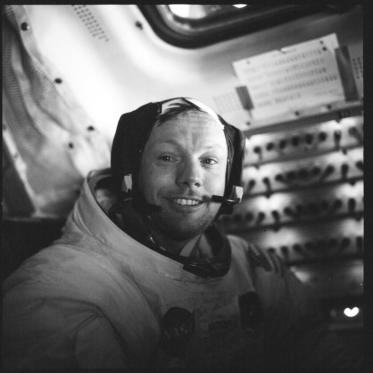 Astronaut Neil Armstrong aboard the Apollo 11 Lunar Module Eagle Man in spacesuit smiles at camera with a panel of switches behind him