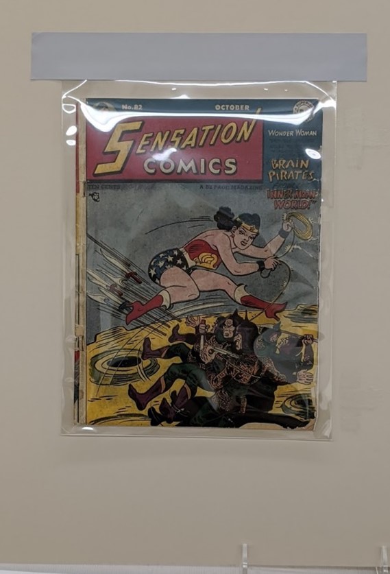 Comic book encased in plastic attached to mat