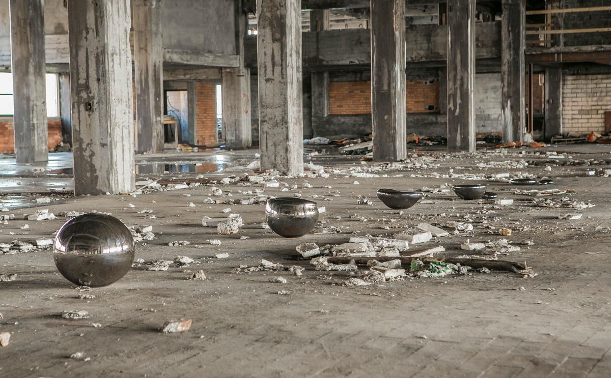 Five silver orbs in a rubble-filled warehouse, each with the top shaved off a bit more till the last one is almost flat