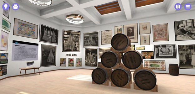 Virtual room with wooden floor and white walls covered with images; stacked barrels in the center of the room
