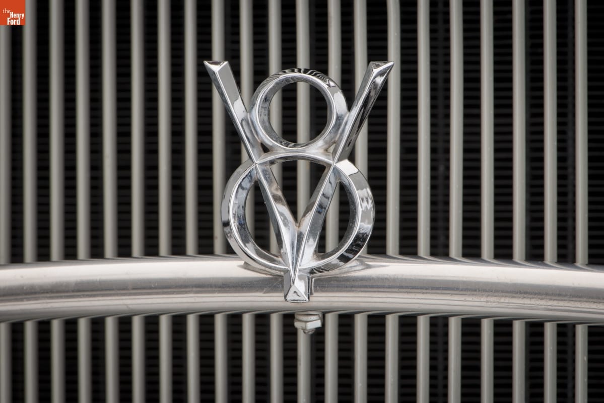 Close-up of car grille with V-8 icon