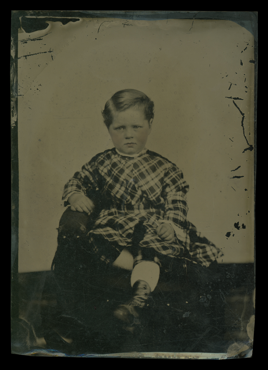 Sitting child in plaid dress
