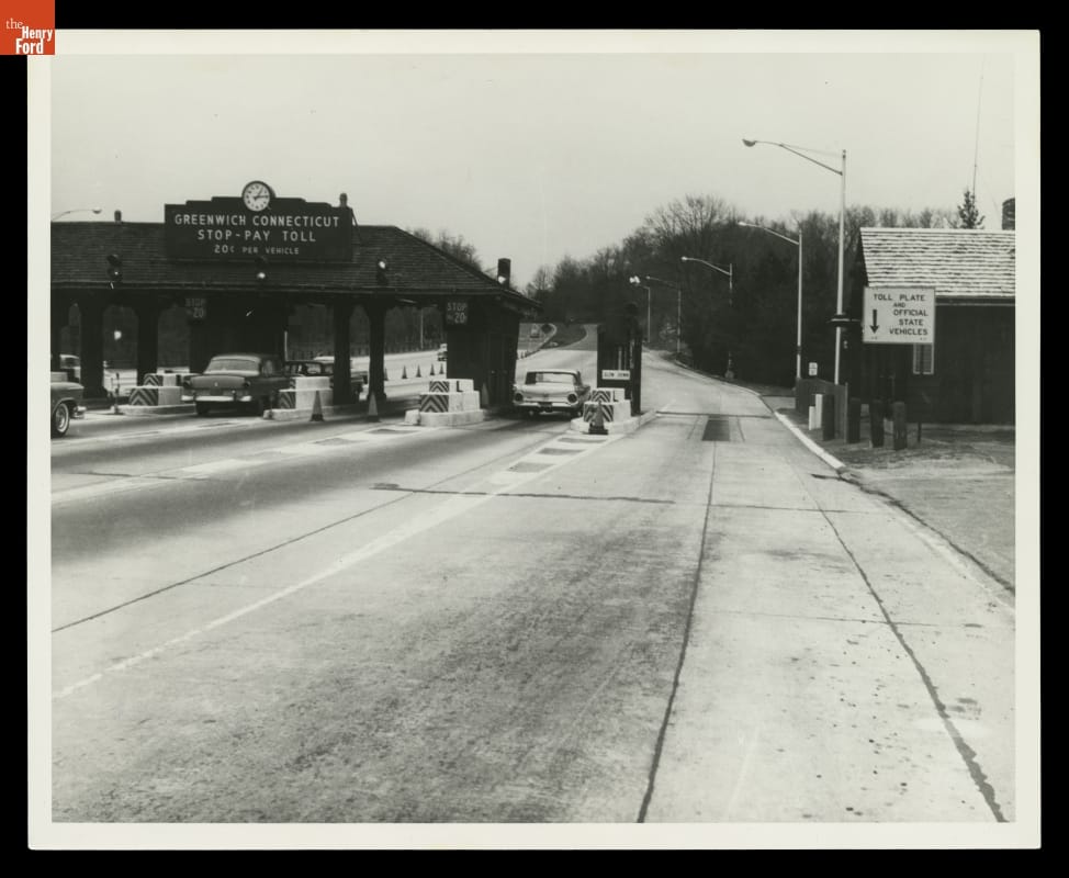 Tollbooths on Merritt Parkway, Greenwich, Connecticut, 1960-1969 Black-and-white photo of tollbooths with cars stopped at them on wide roadway