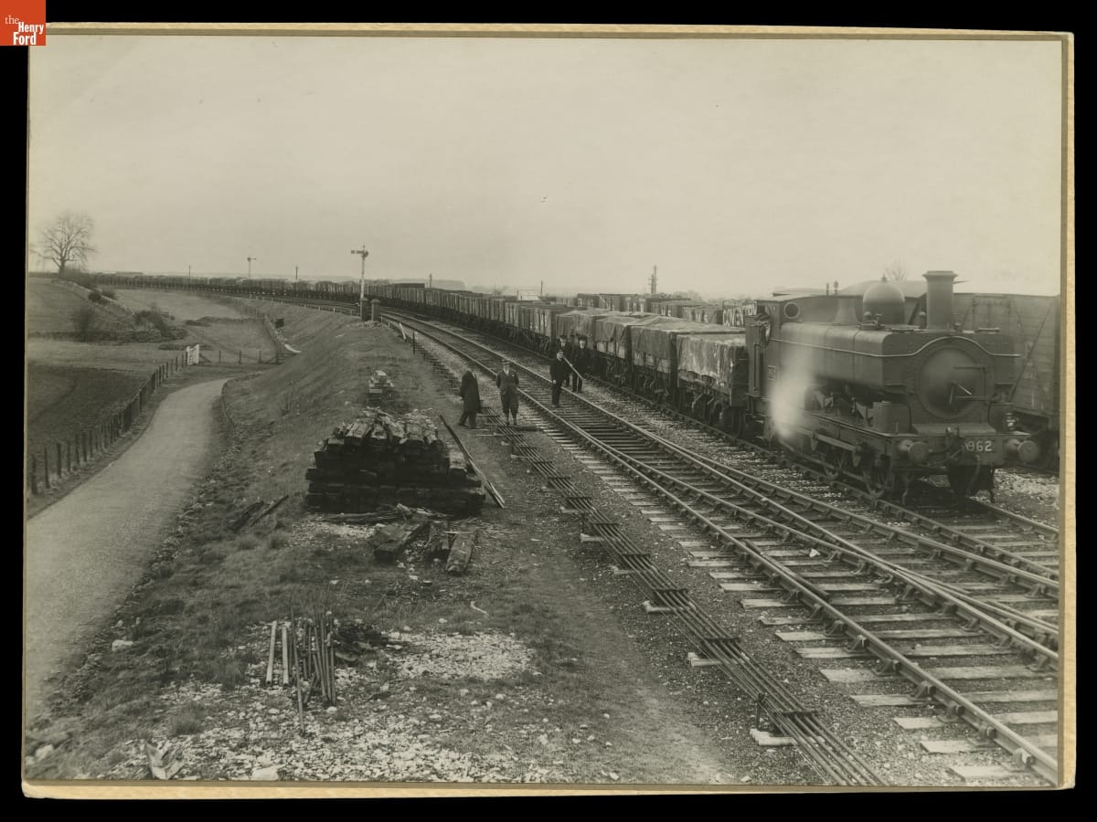 Railroad Cars Carrying the Dismantled Cotswold Cottage Away from Its Original Site in England, 1929-1930 Train with many open cars packed with pallets