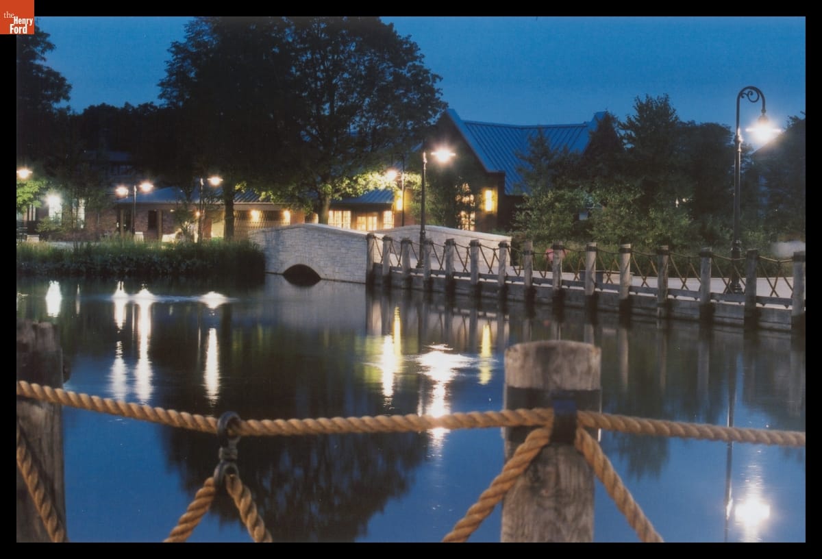 Greenfield Village in Evening, 2004 Pond at dusk, surrounded by wood and rope rails, with building(s) in the background