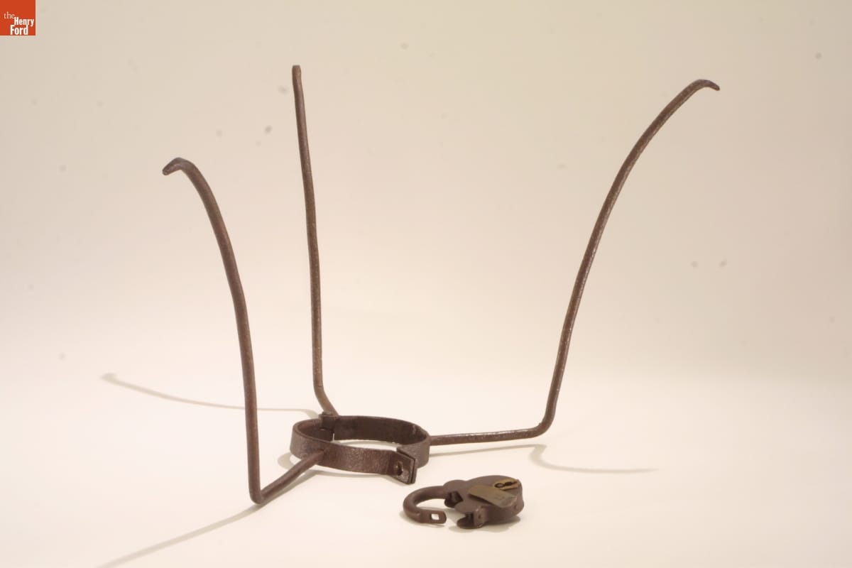 Metal collar with three tall prongs extending upward and outward; lock nearby