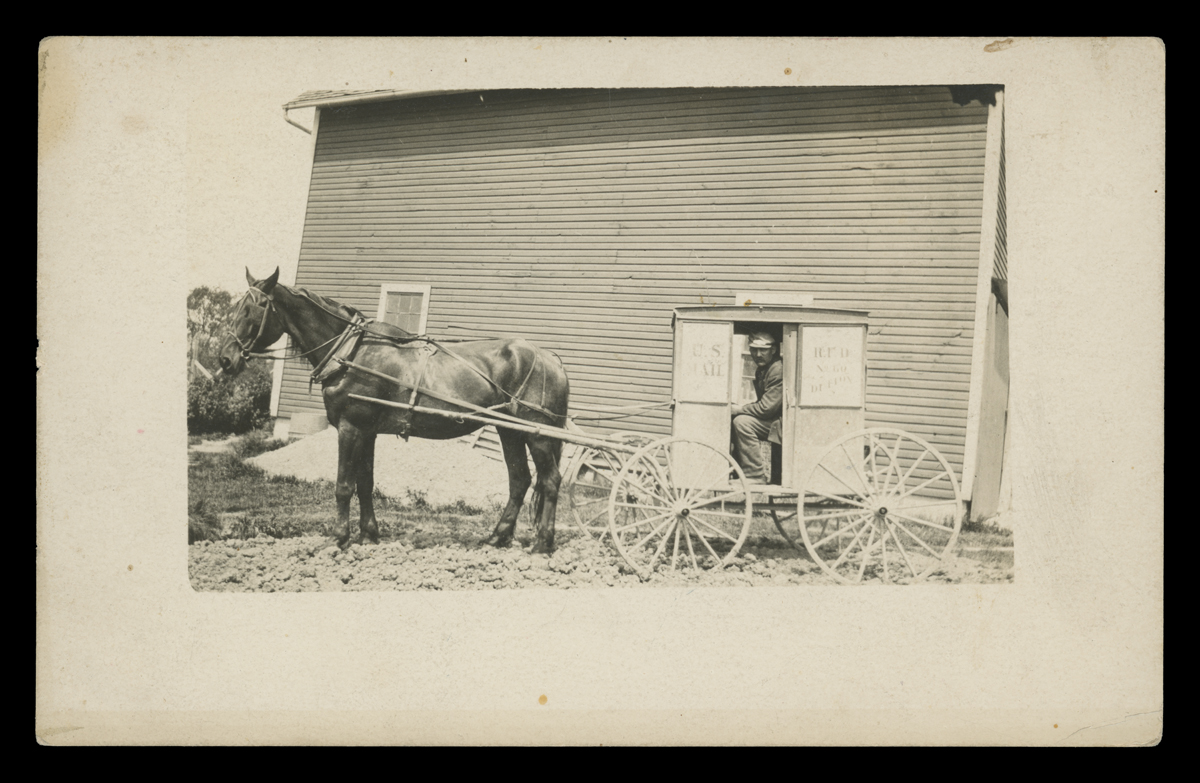 Rural Free Delivery in a Horse-Drawn Mail Delivery Wagon, 1895-1920 Man sits in very small boxy cart/wagon hitched to a horse in front of a building
