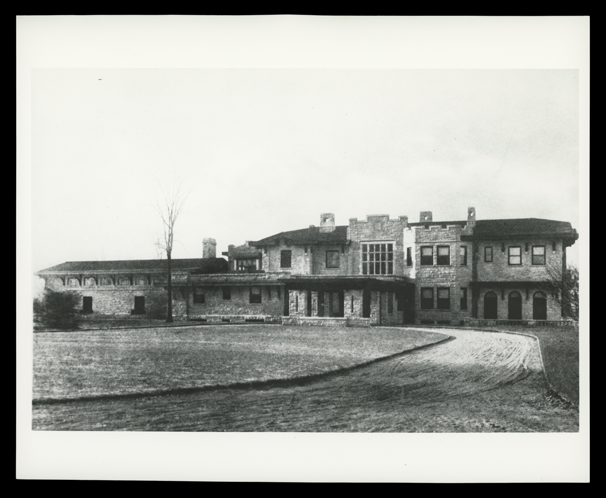 Black-and-white photo of large stone house with turrets