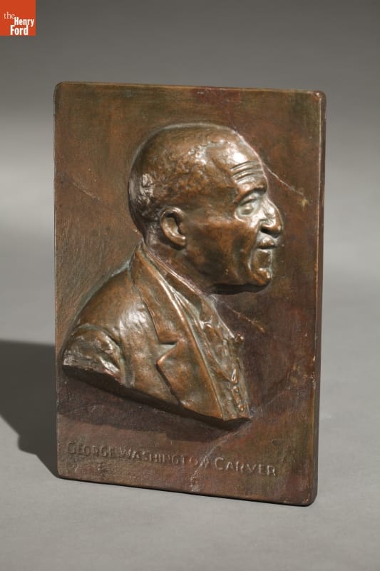 Bronze-colored metal plaque with raised portrait of man's head and shoulders