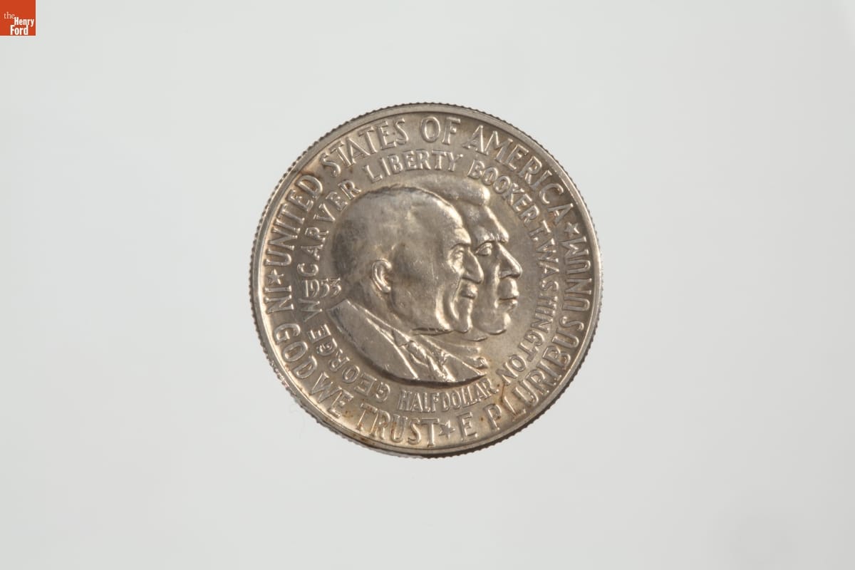 Silver coin with text and two men's faces in profile