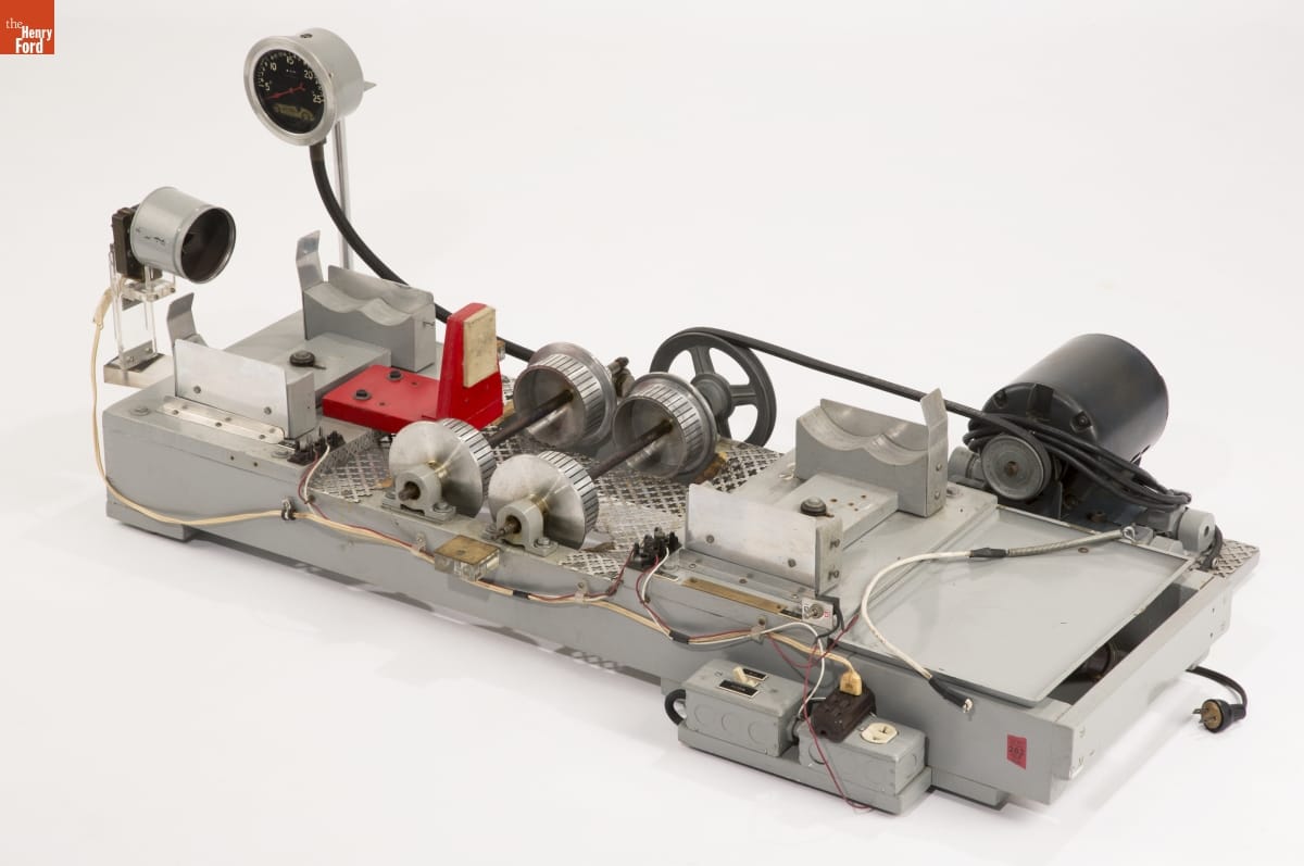 Piece of equipment with silver metal rectangular base with gears, wires, and other components