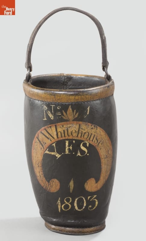 Fire Bucket, 1803 Tall, narrow, black leather bucket with a handle, with writing and decoration on side