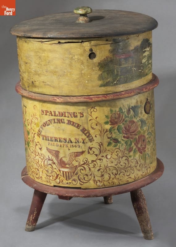 Yellow, drum-shaped form painted with text and decorations, on wooden stool with three legs