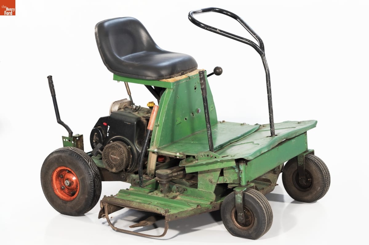 Minimal riding lawnmower, with open green base topped with black seat with machinery underneath