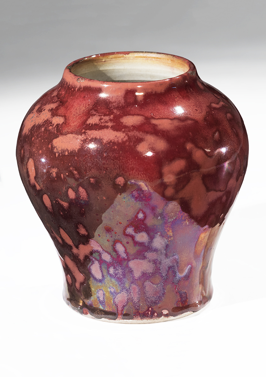 Small vase with narrow base rounding out, then narrowing again at mouth, with mottled reddish colors ranging from peach to dark maroon