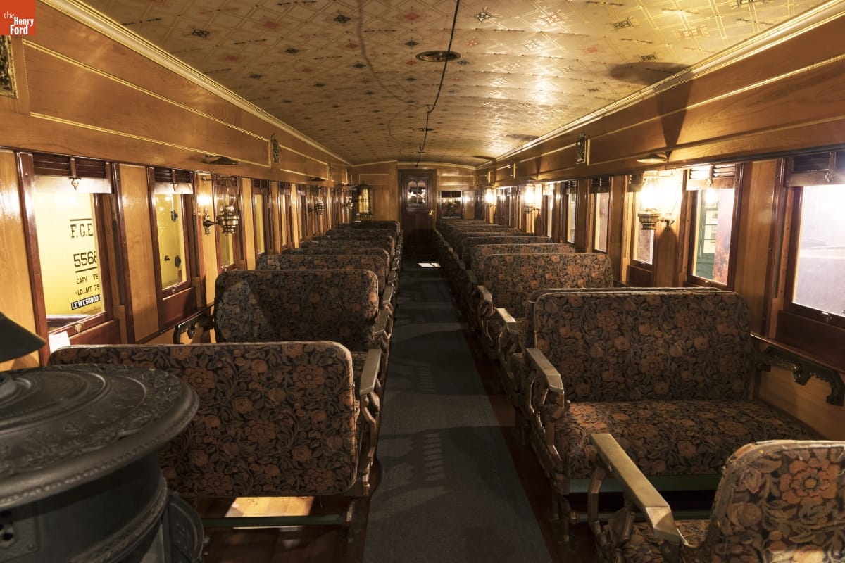 Bangor & Aroostook Railroad Passenger Coach Replica, Interior Interior of rail car with floral-upholstered bench seats, wood paneling, and decorative ceiling