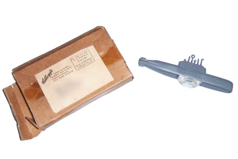 Gray plastic toy submarine, 1954, along with brown cardboard box with mailing label showing Kellogg’s as sender