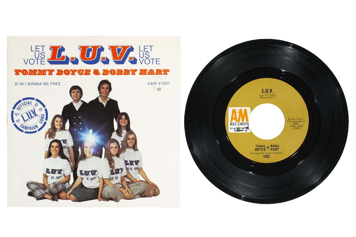 Record cover featuring a group of people and text, sitting next to a single record