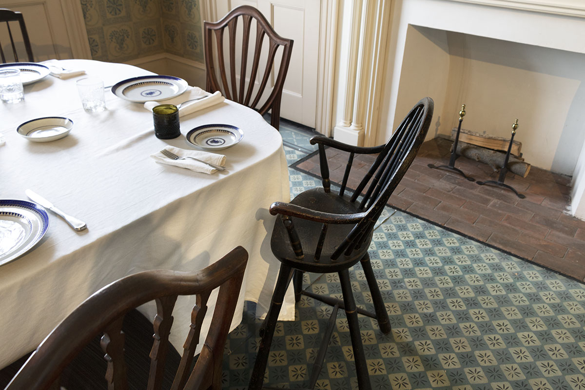 Noah Webster Home / highchair Corner of set table with mismatched chairs; fireplace behind