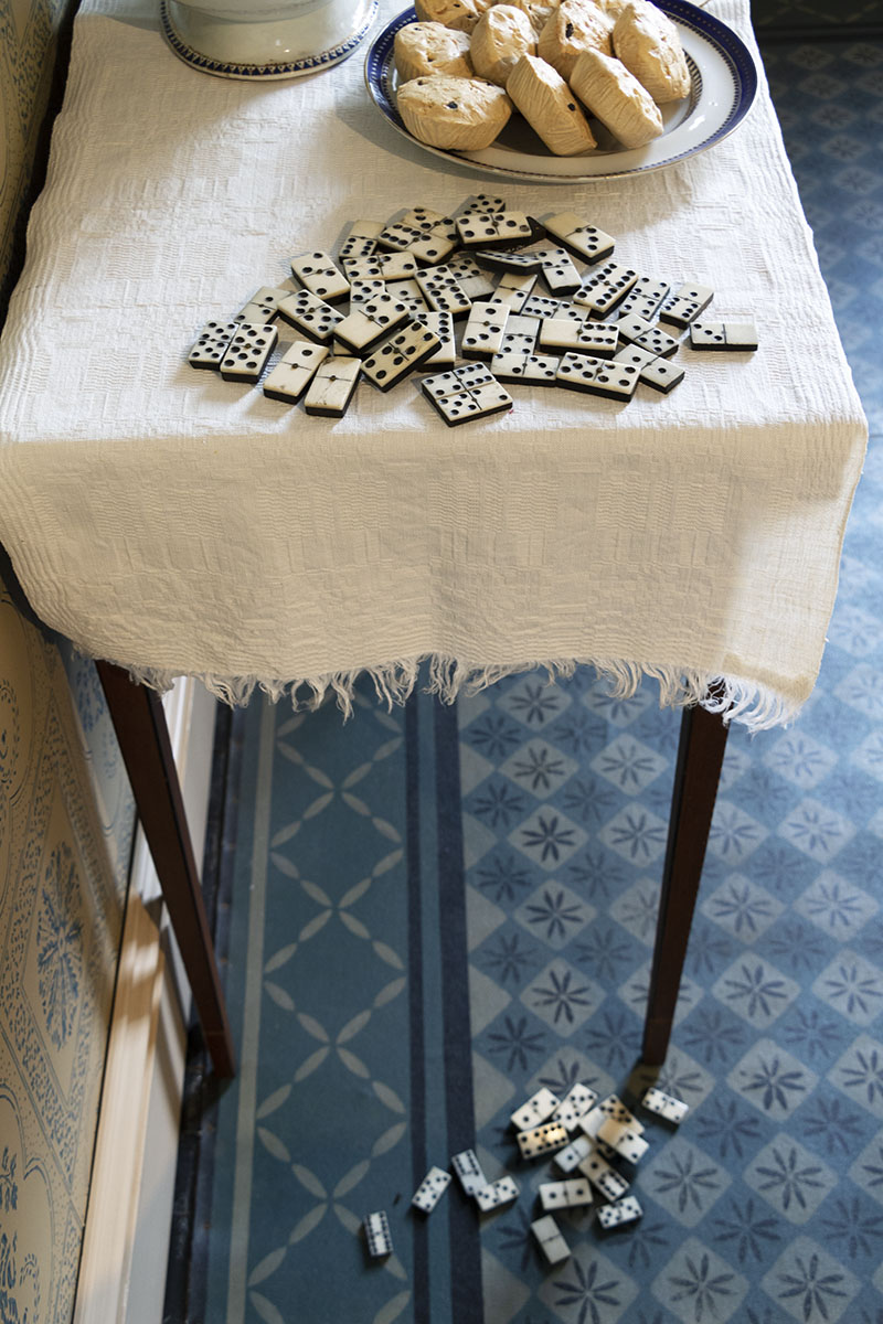 Noah Webster Home / dominos End of table covered with cloth with dominos and plate of scones on it; additional dominos on patterned floor below